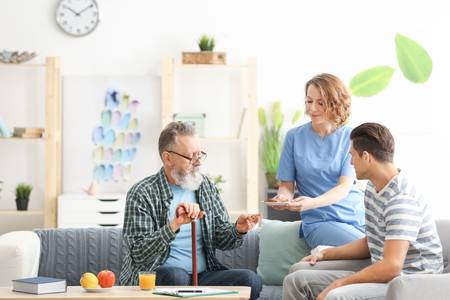 Nurse offering assistance to elderly patient and grandson